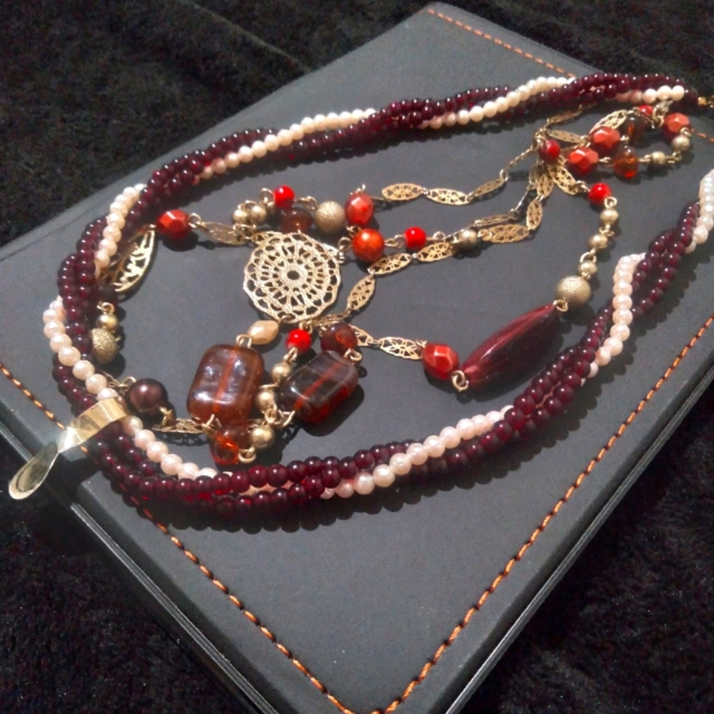 2 necklaces 1.long gold tone filigree/amber/purple beads 2. Is faux pearl/ruby